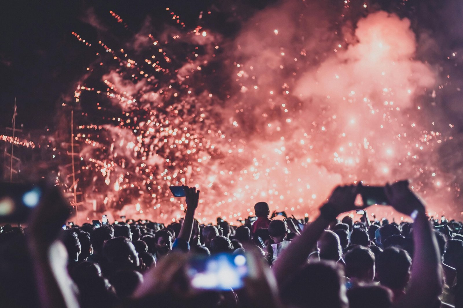 A high-energy music festival crowd enjoying fireworks and live performance at night.